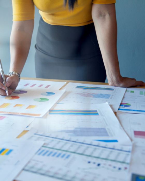 Woman leaning over table covered in finance documents.