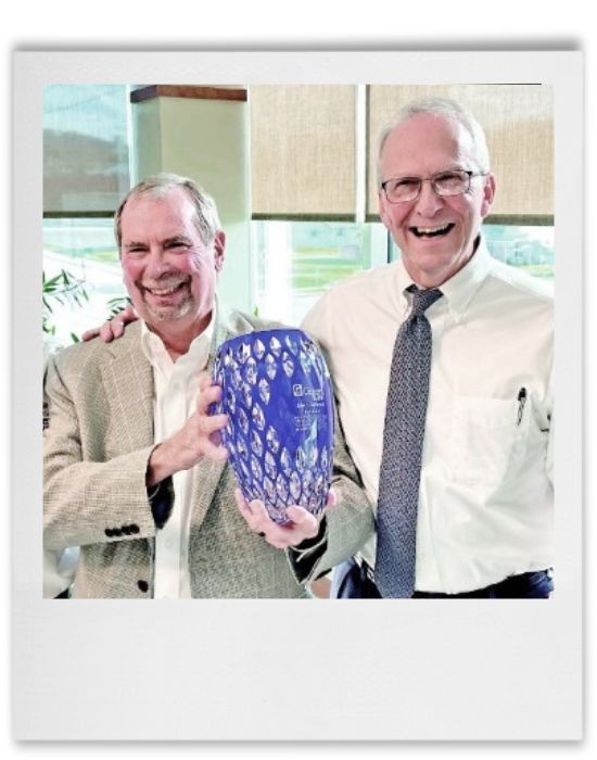 two men holding a vase smiling.