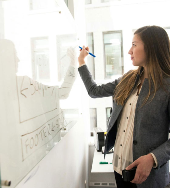 A lady using a white board in an office