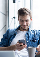 Man using a smartphone while drinking coffee