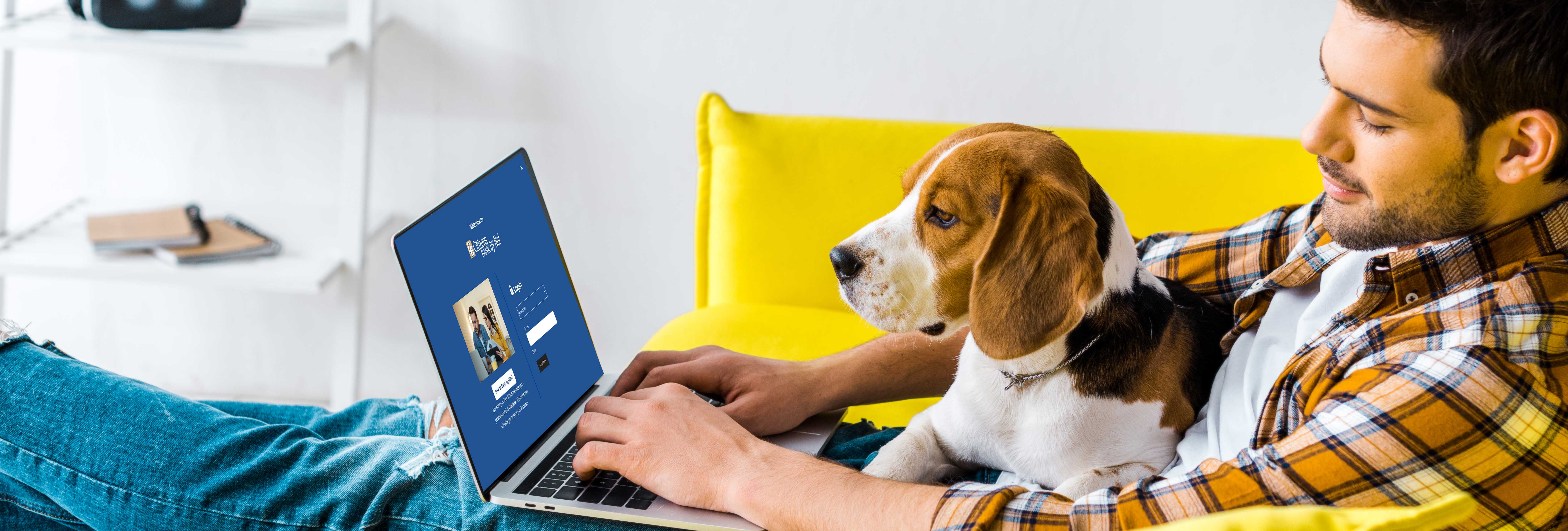 man using online banking with dog in lap